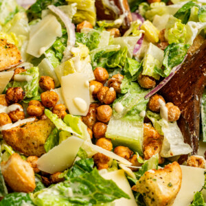Dressing tossed into a bowl of caesar salad.