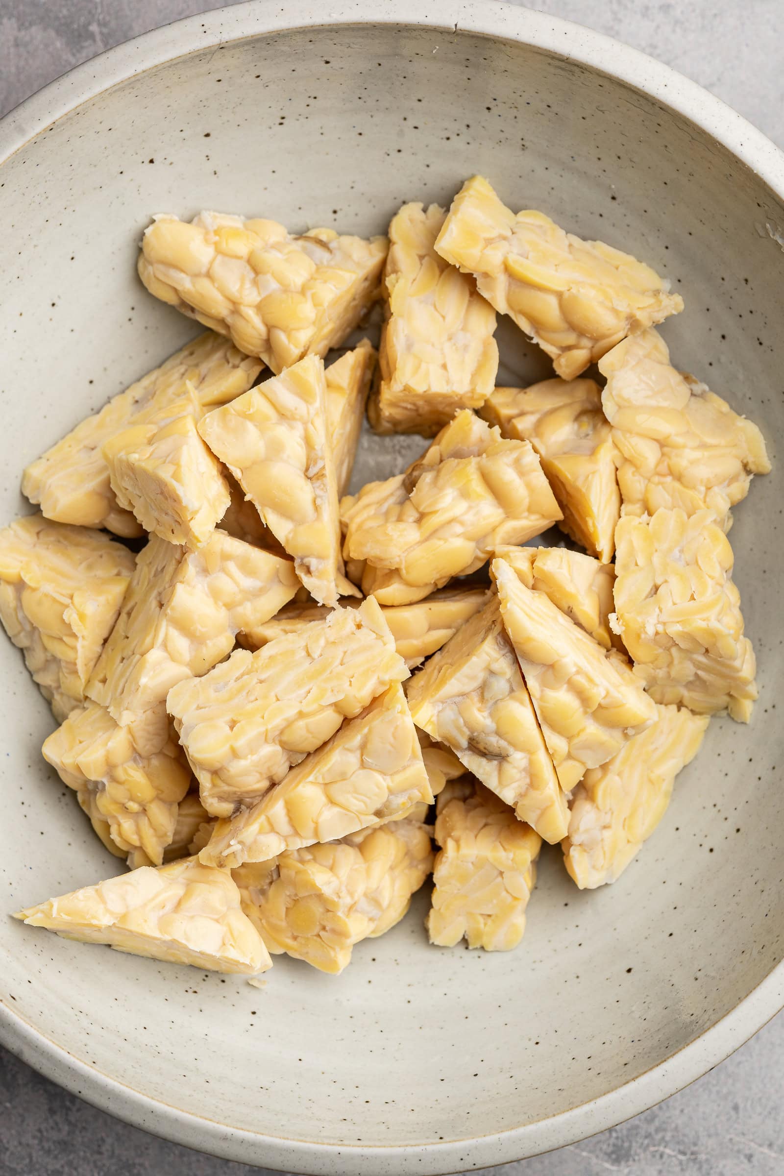 Tempeh cut into triangles in a bowl.
