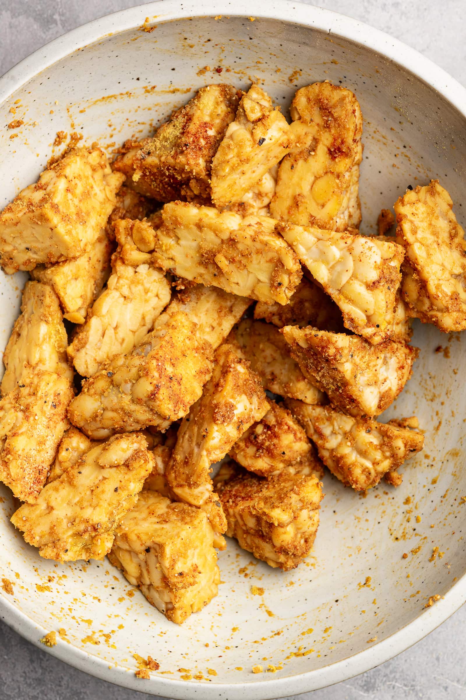 Tempeh cut into triangles and tossed in seasonings.
