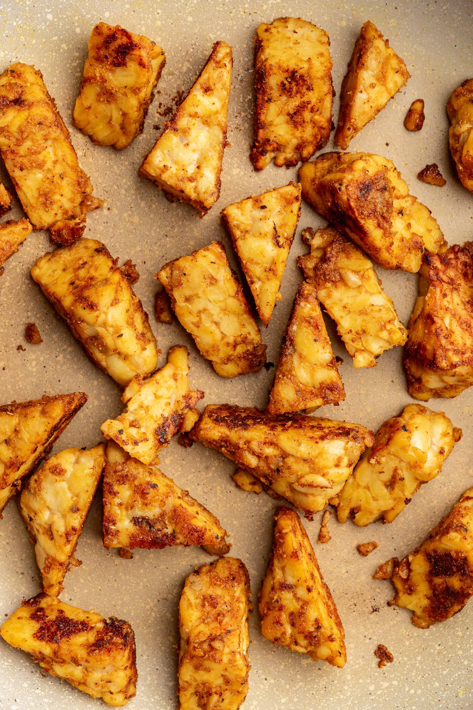 Pan-fried tempeh in a pan.