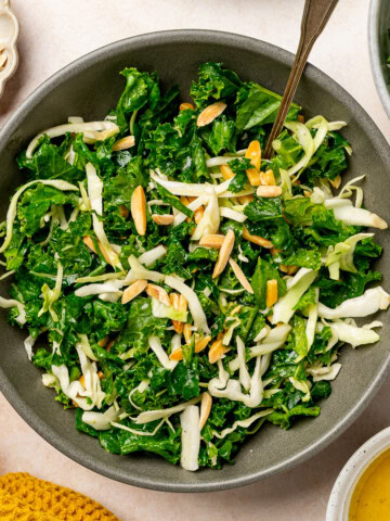 kale cabbage salad with slivered almonds in serving bowl.