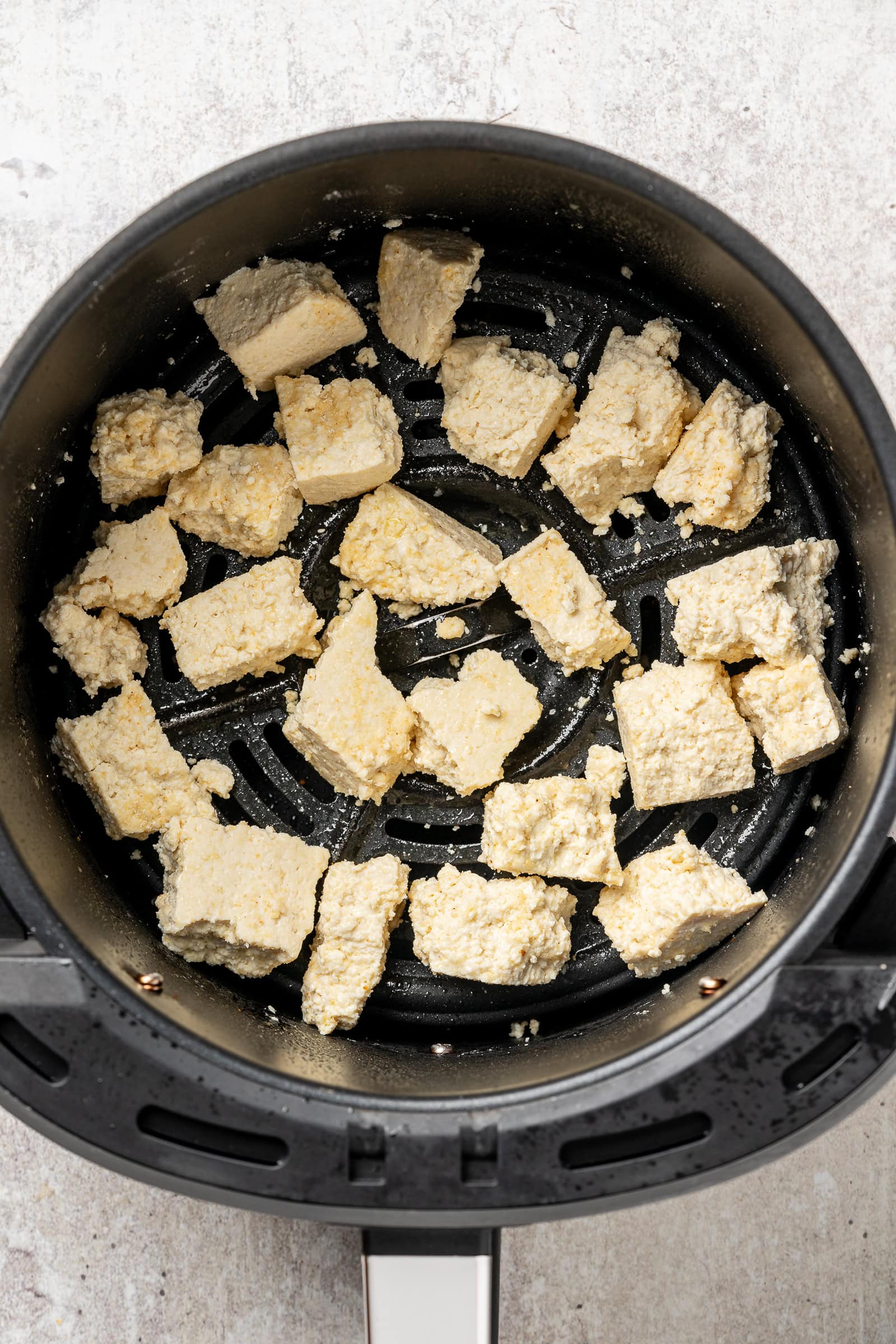 Tofu in an air fryer basket before air frying.