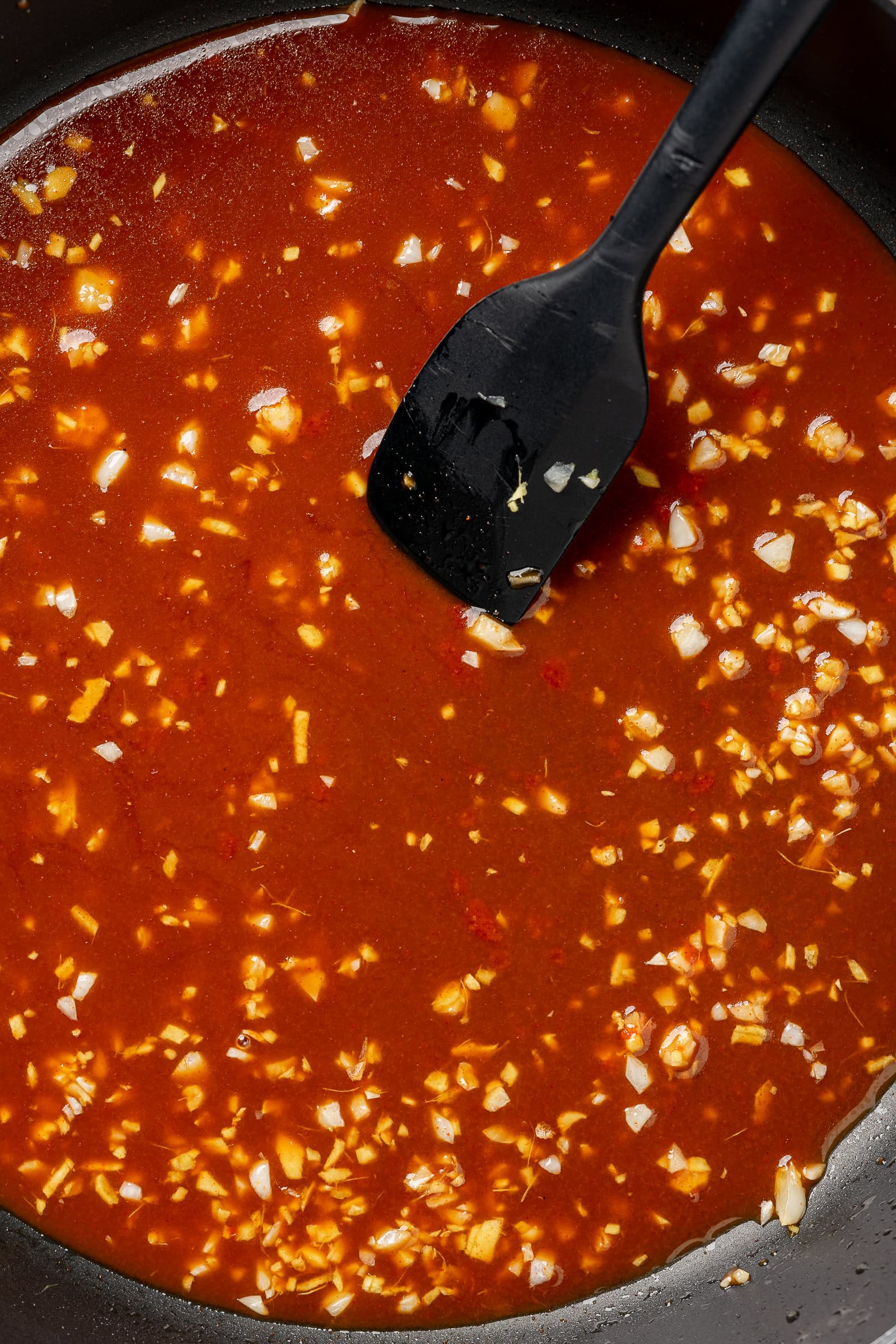 Sauce added to a frying pan with aromatics.