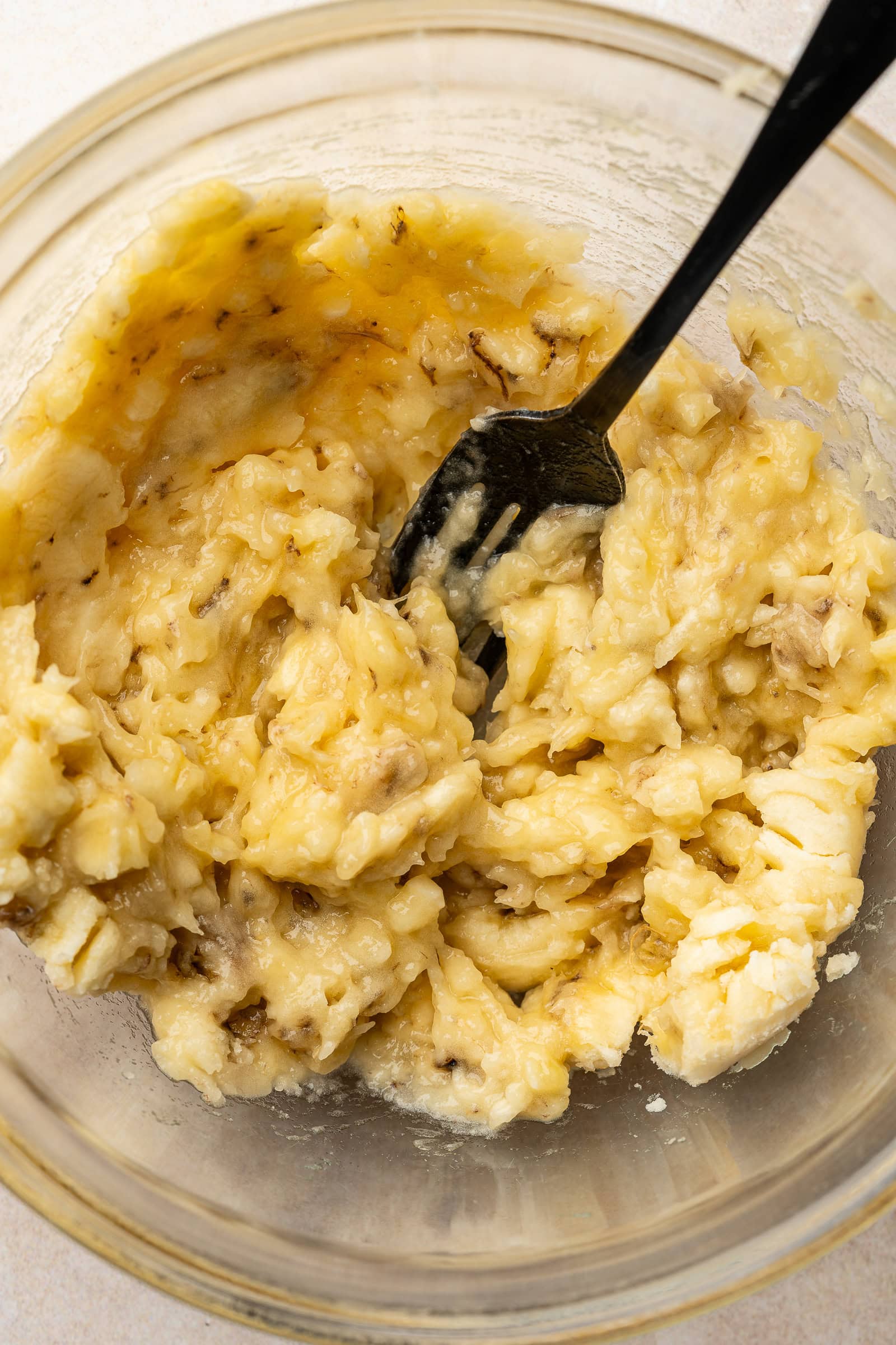 Mashed ripe bananas in a glass bowl.