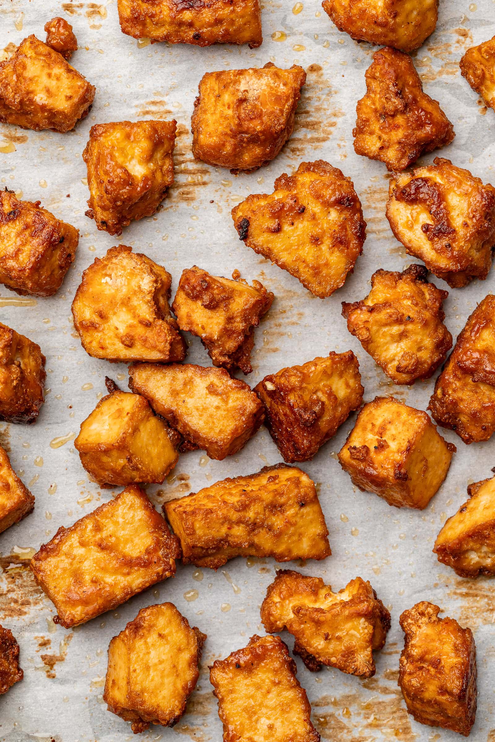 Baked tofu chunks on a parchment lined baking tray.