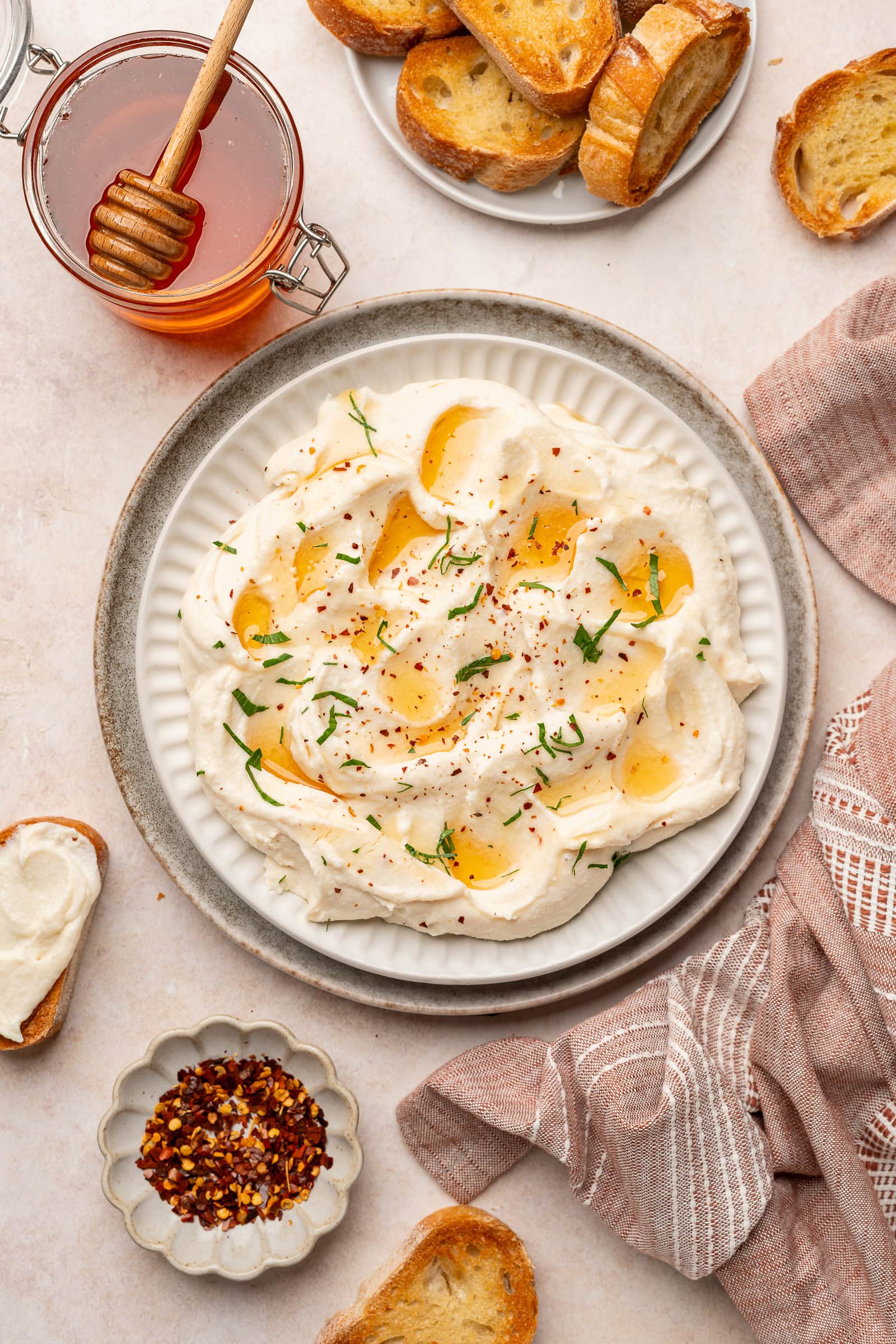 Vegan feta being plated on a serving dish, garnished with hot honey and parsley.