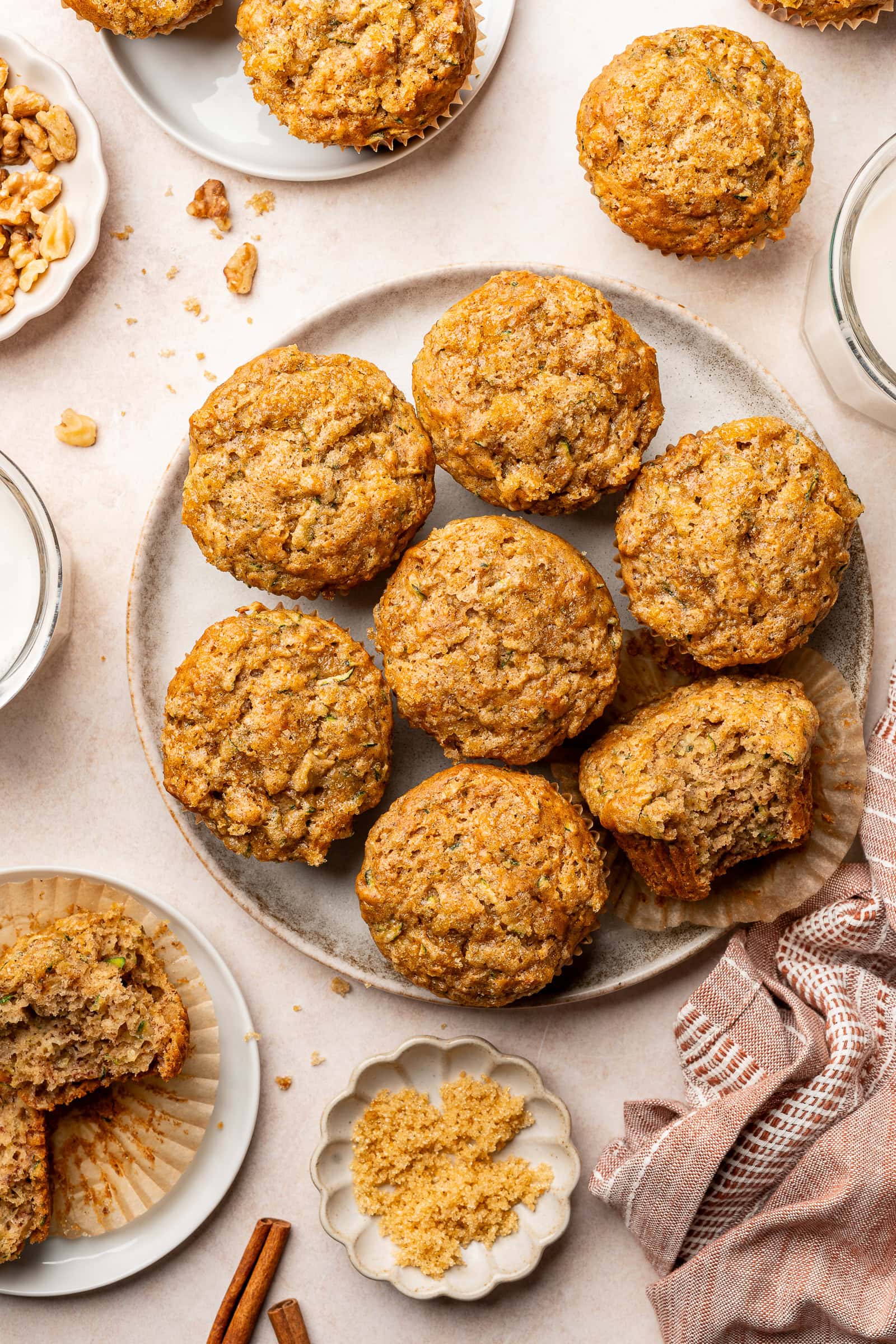 Banana zucchini muffins on a serving plate, one with bite taken out.