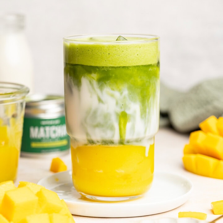 Matcha layered into a glass with layers of mango purée and oat milk.