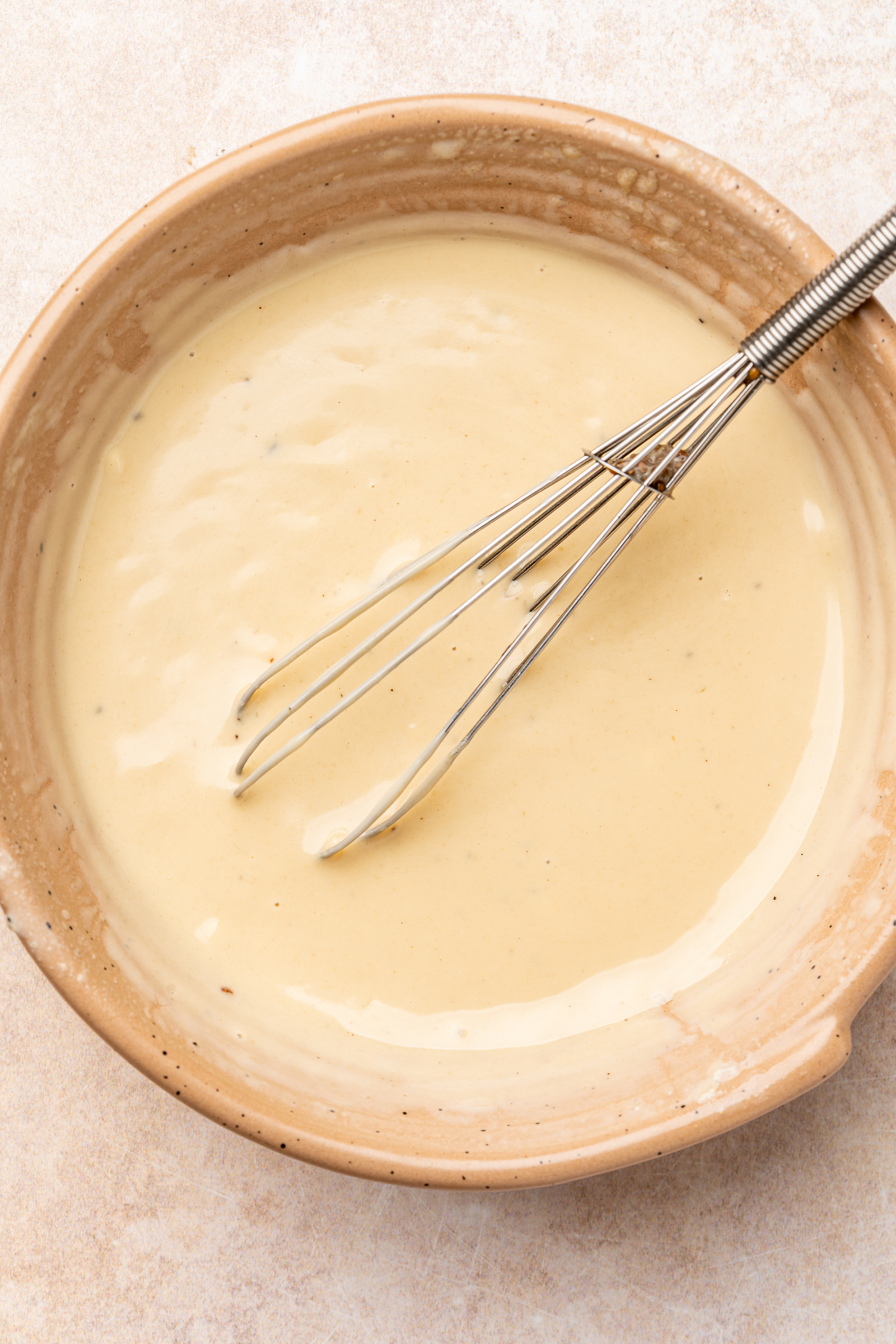 Water being whisked into the tahini dressing to thin it out.