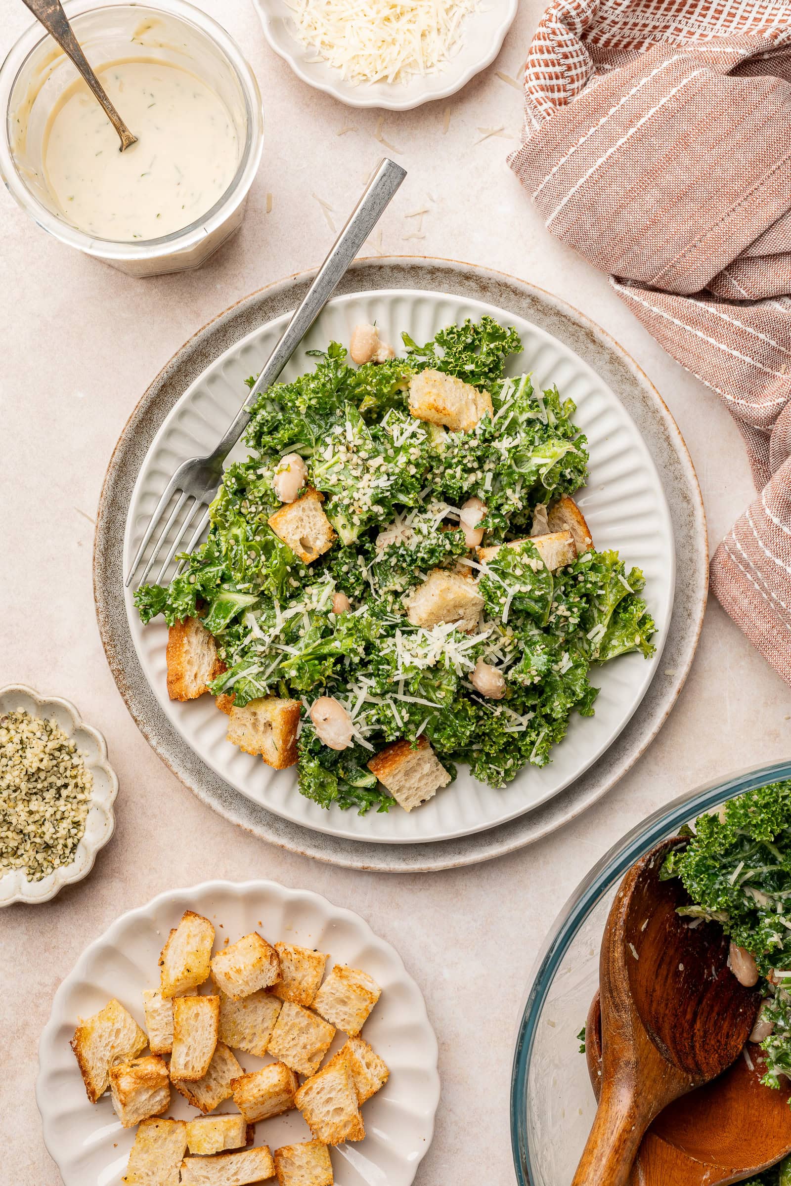 Kale salad with white beans and croutons on a serving plate with tahini dressing.