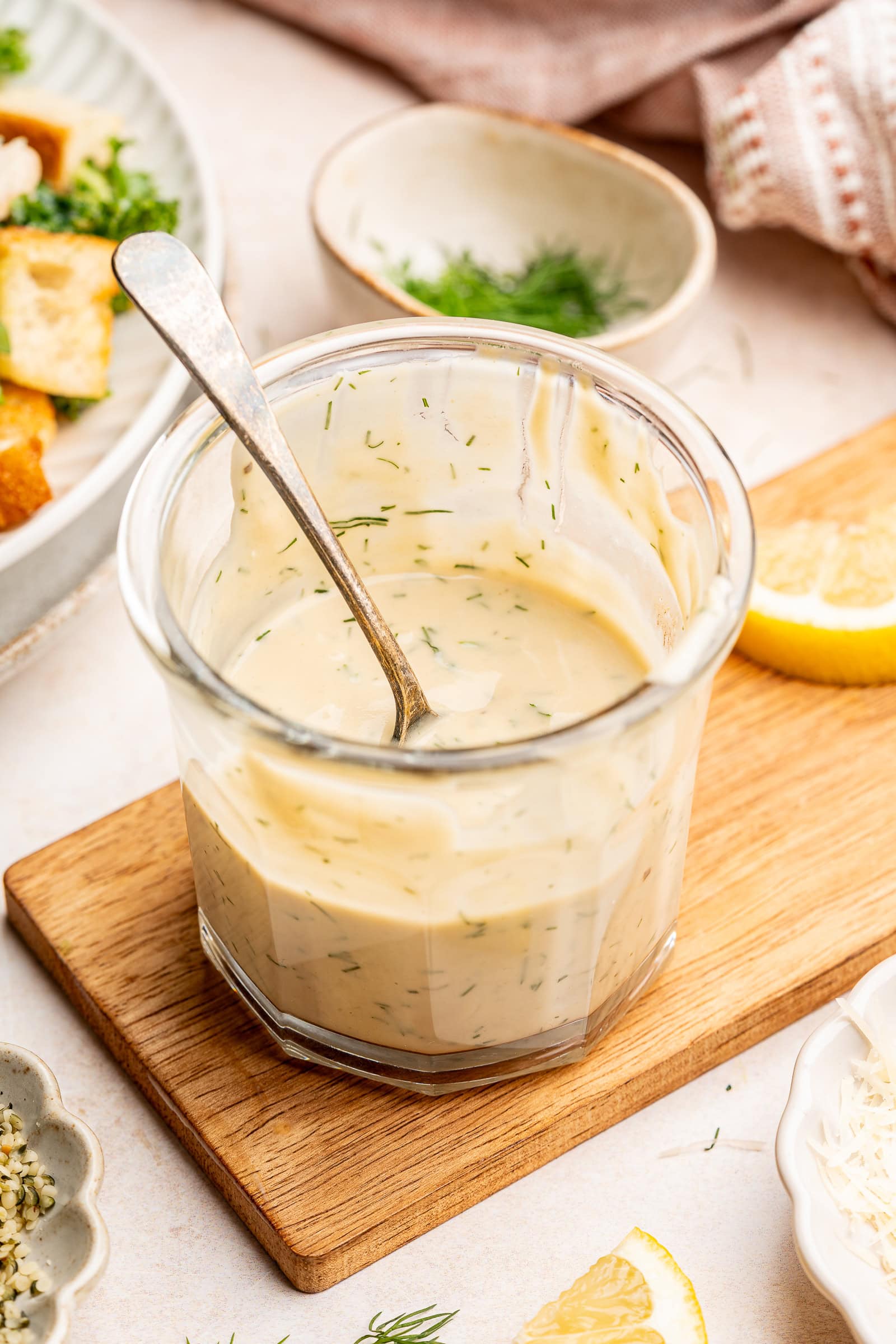 Tahini dill dressing in a glass jar with a serving spoon.