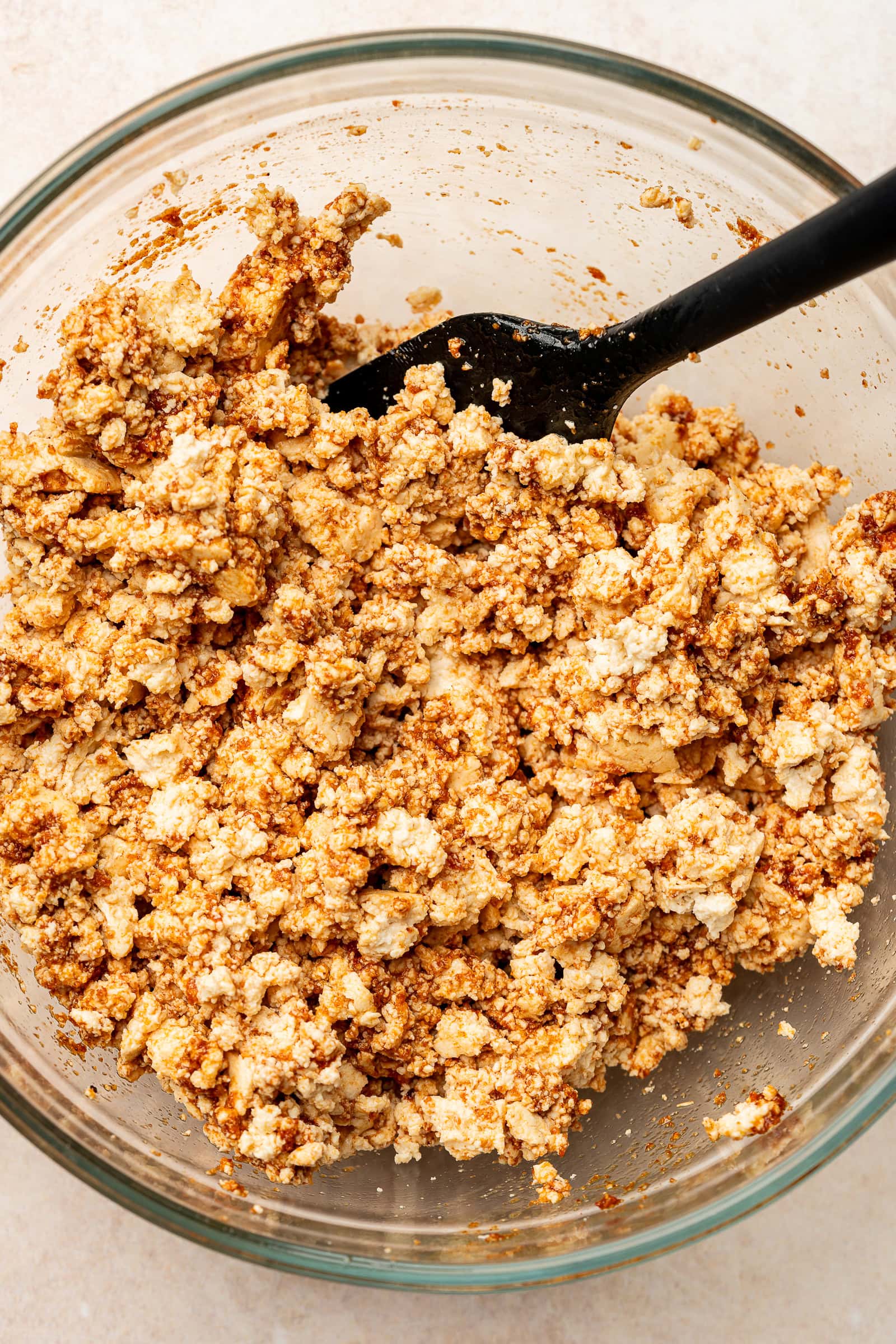 Crumbled tofu tossed in spice tomato paste mixture in large bowl.