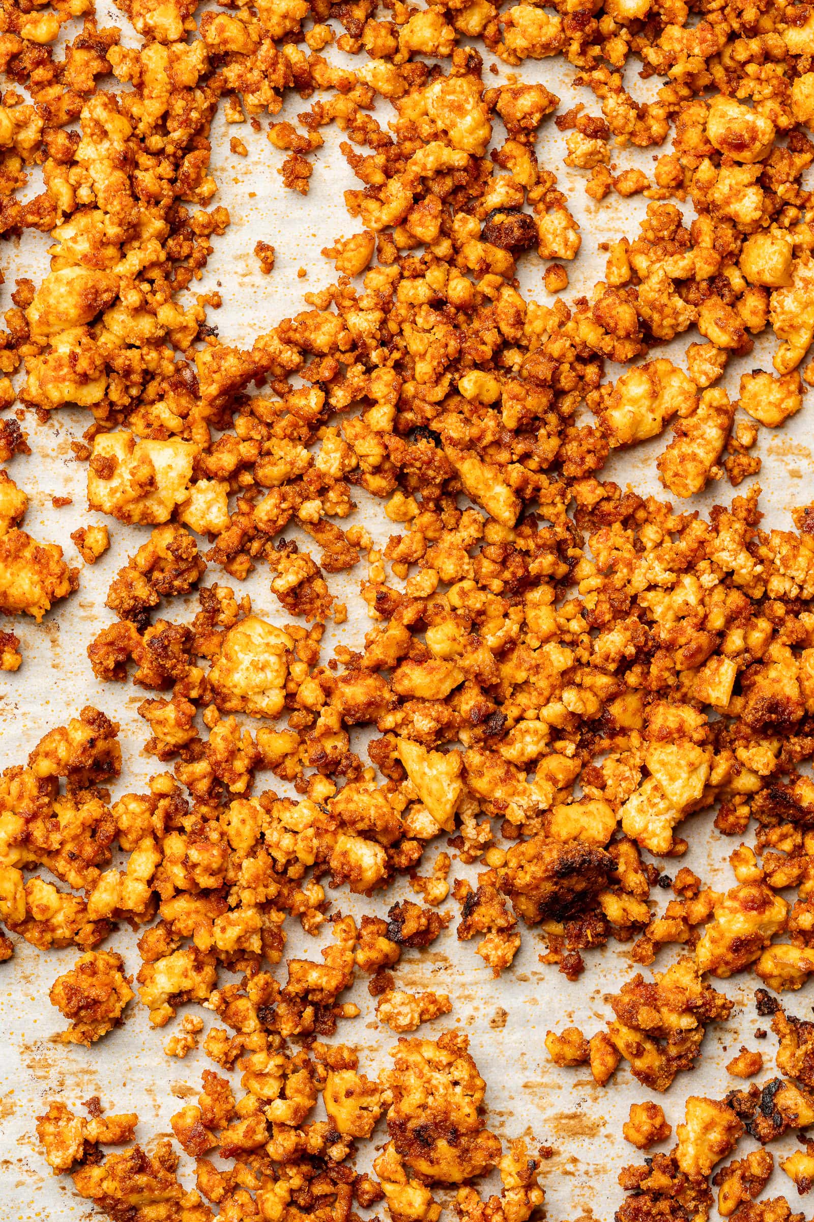 Baked tofu crumbles on a parchment lined baking sheet.