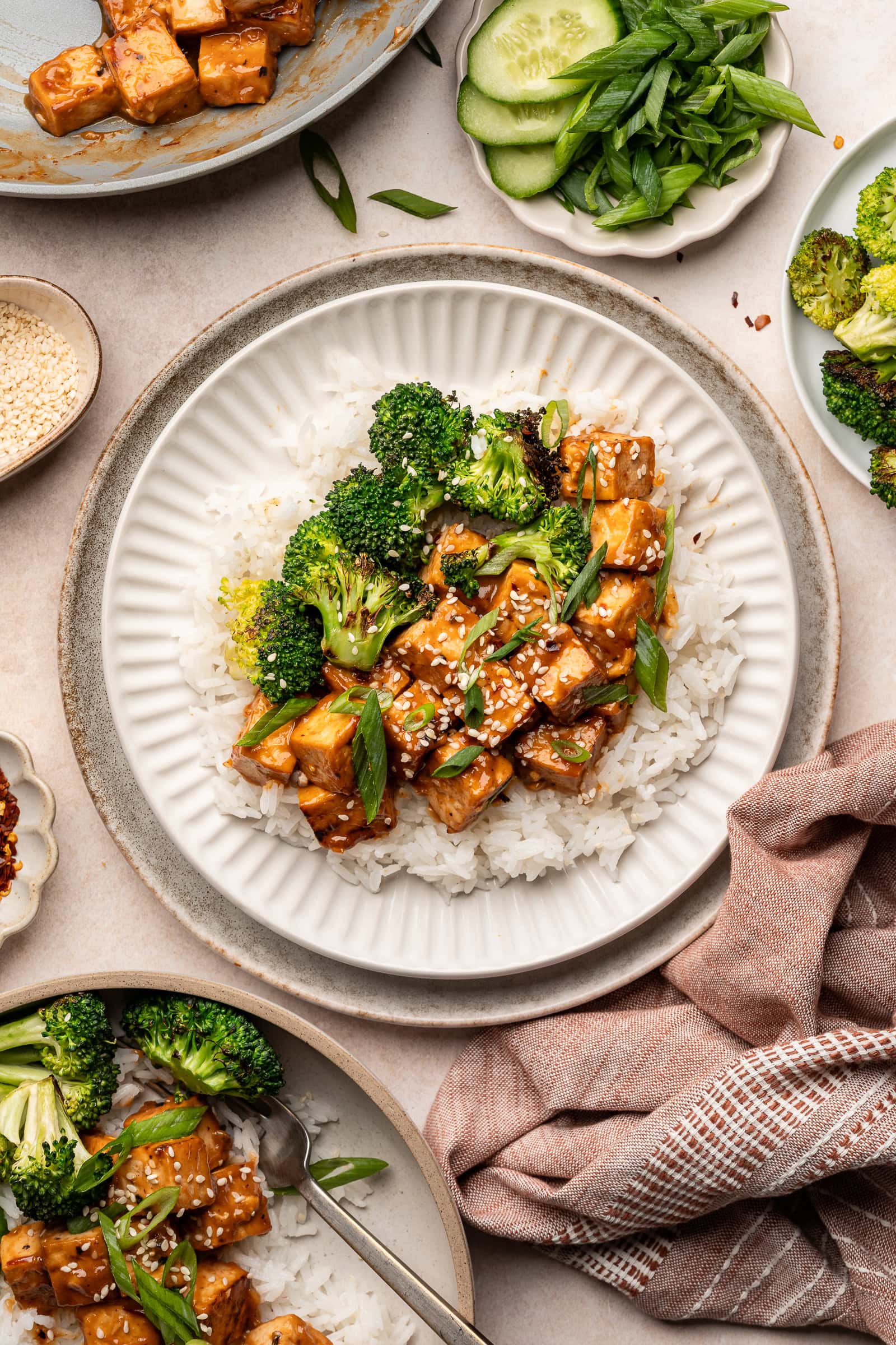 Miso glazed tofu on top of a bed of rice with charred broccoli, sesame seeds, and green onions.