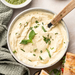 Tofu ricotta in a serving bowl with a spatula and garnished with basil.