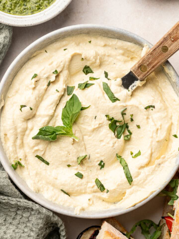 Tofu ricotta in a serving bowl with a spatula and garnished with basil.