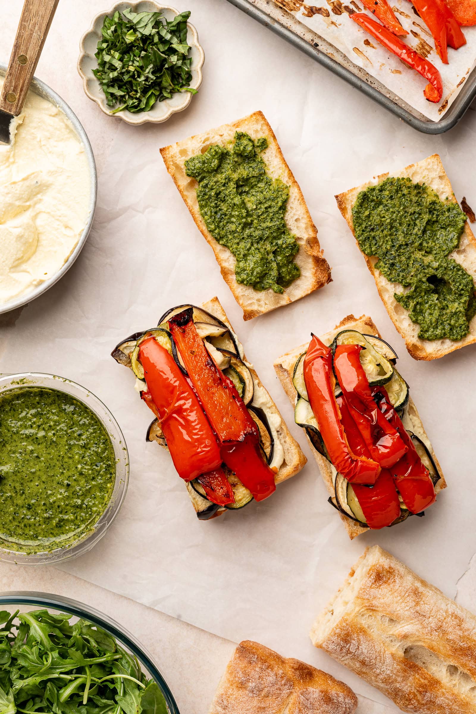 Sandwiches being stacked with roasted veggies.
