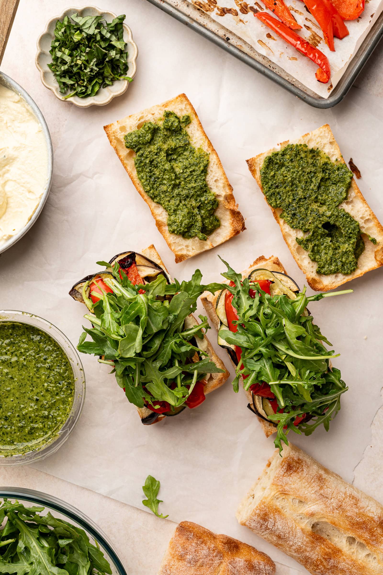 Arugula being placed on sandwiches.