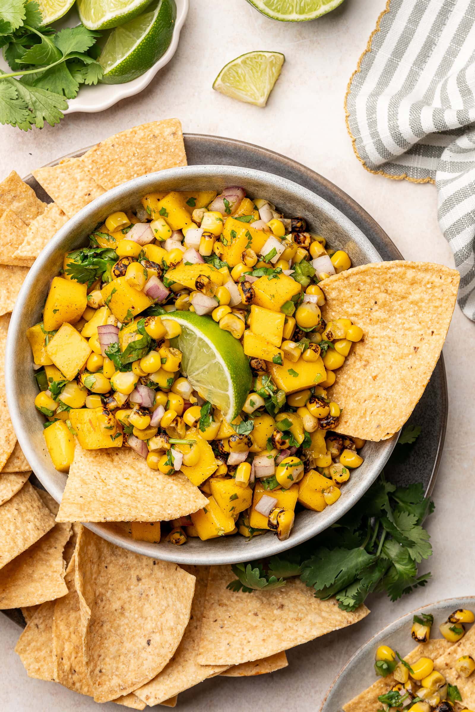 Corn mango salsa in a serving dish with tortilla chips and a lime wedge garnish.