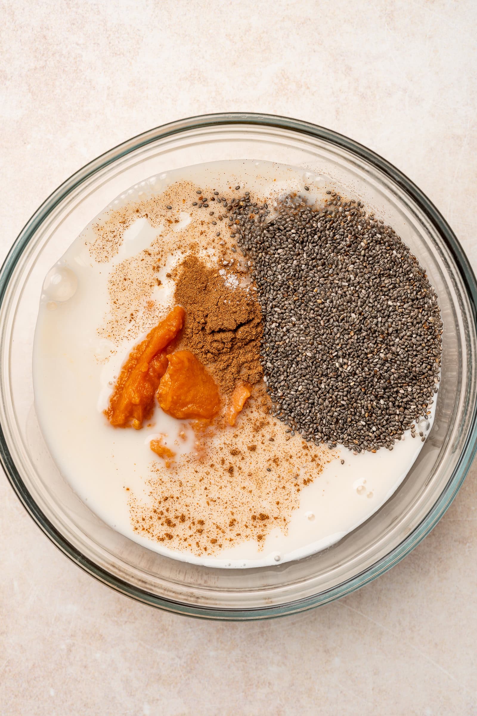 Pumpkin pie chia pudding ingredients in a glass bowl before being mixed.
