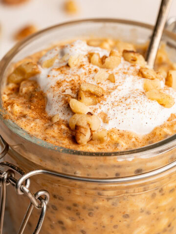 Set overnight oats in a small glass jar topped with coconut whip, walnuts, and a sprinkle of cinnamon.