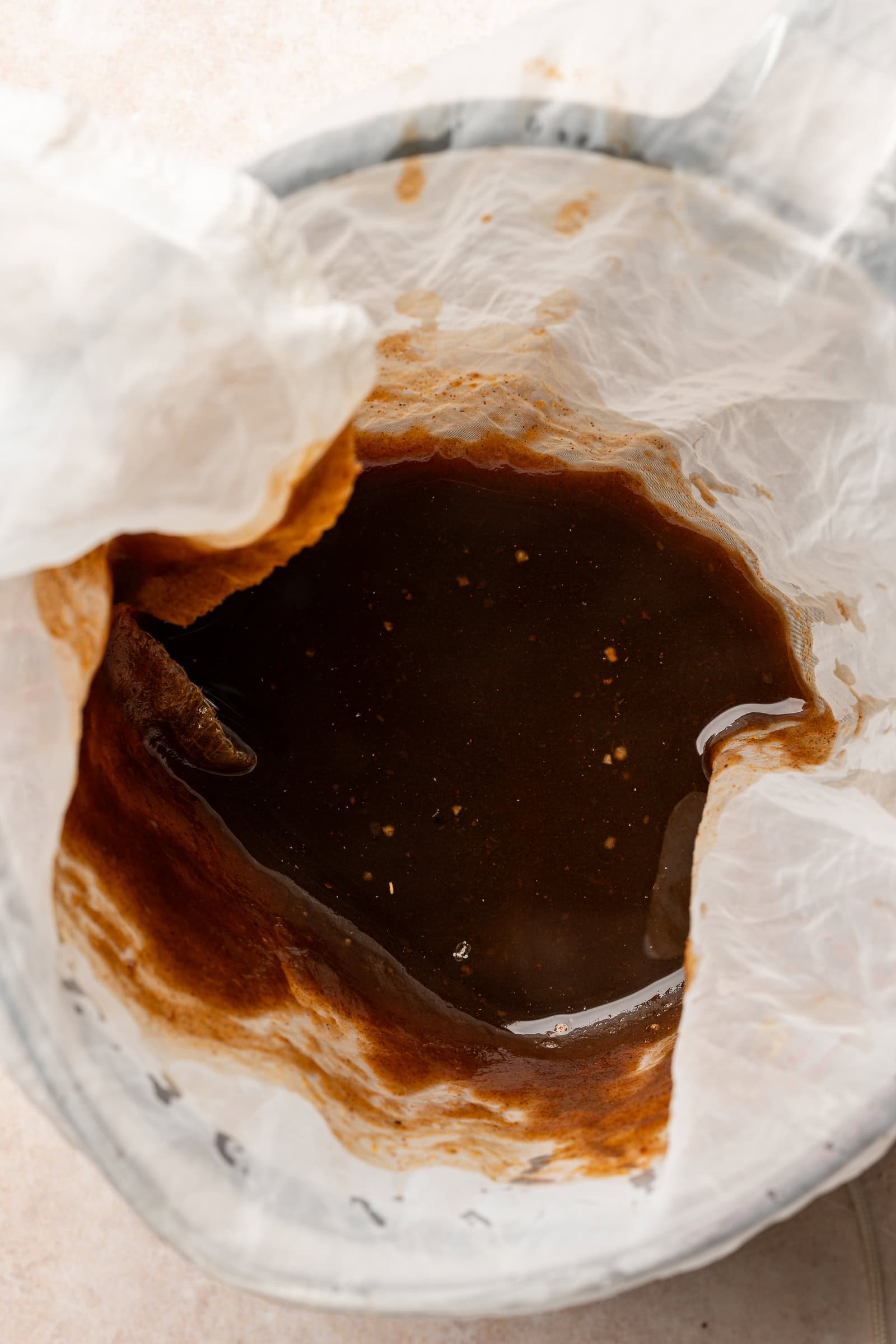 Pumpkin spice syrup being strained through a nut milk bag.