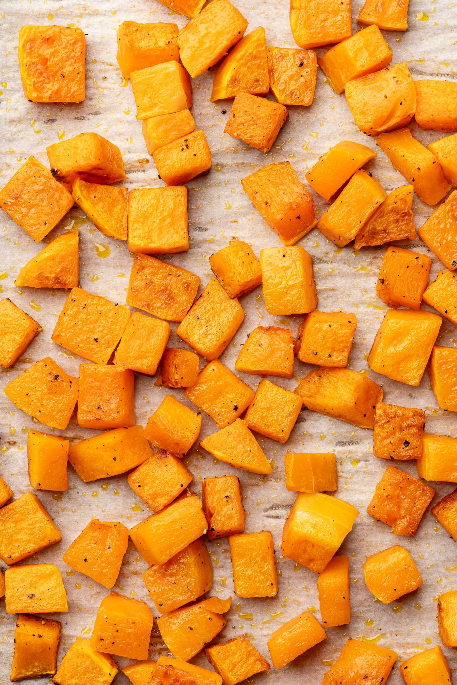 Roasted butternut squash on a parchment lined baking sheet.