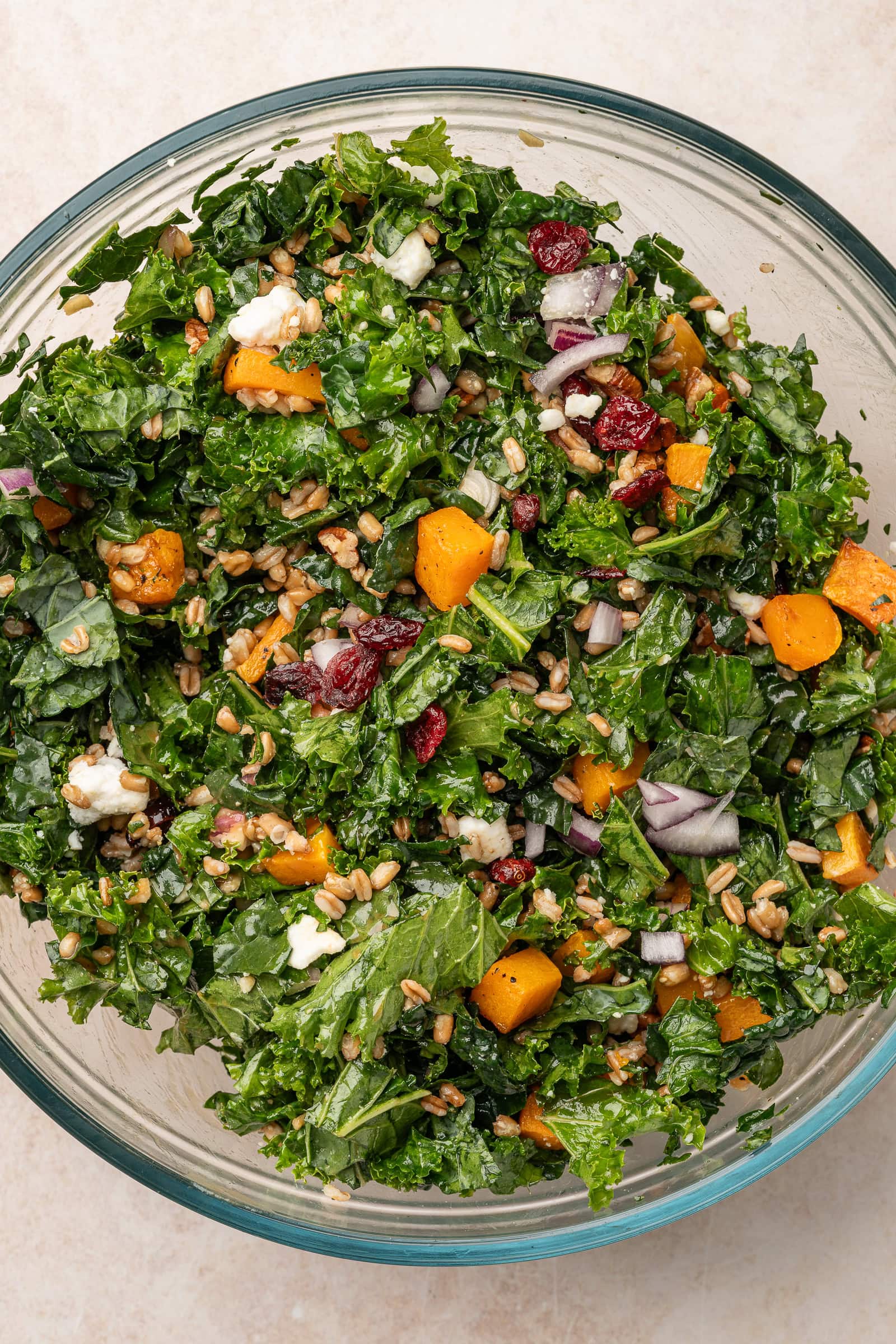 Butternut squash farro kale salad tossed together in a large glass bowl.