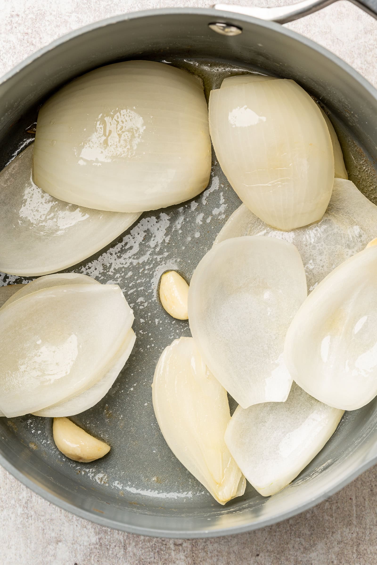 Wedged onion and whole garlic cloves in a pan with melted butter.