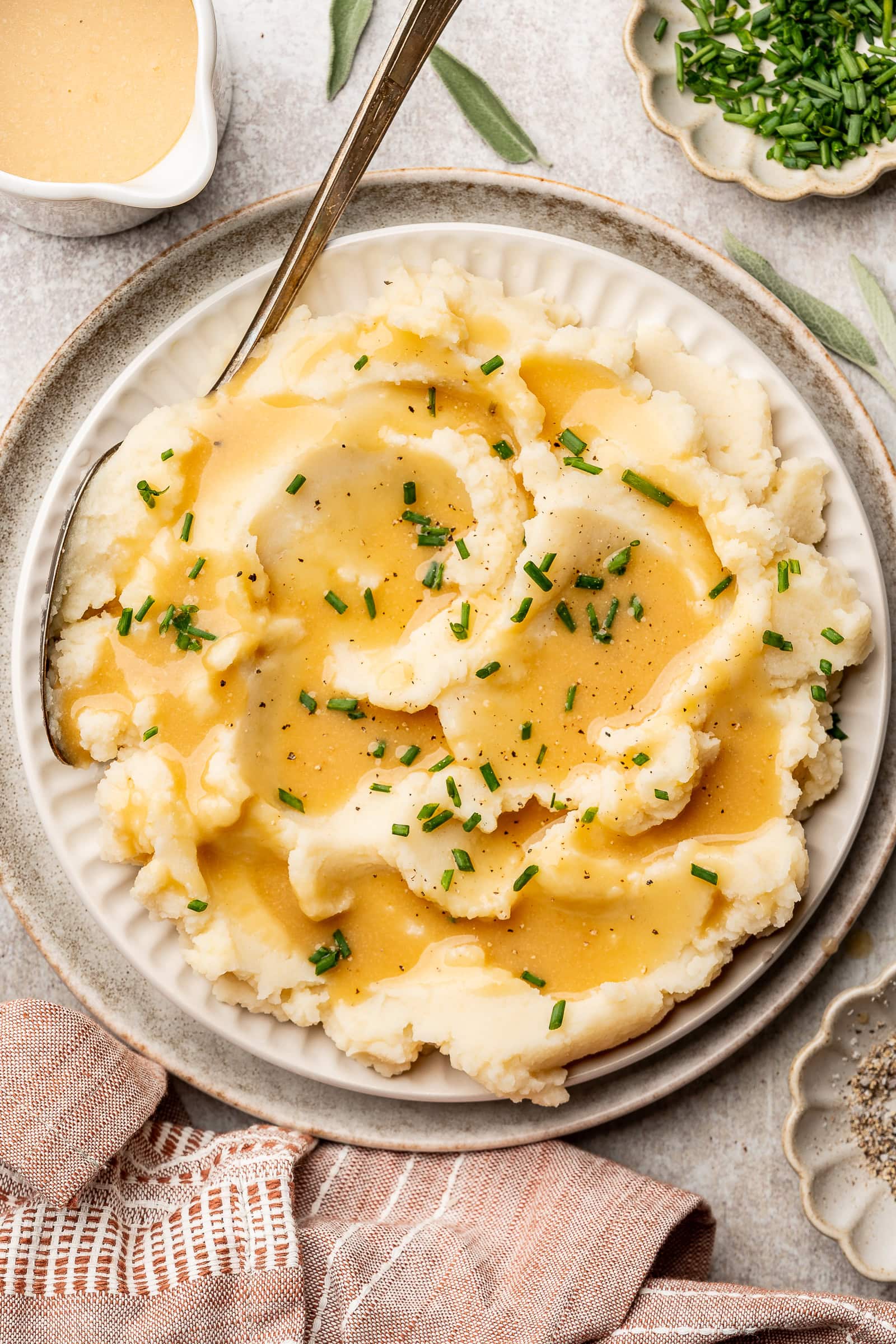 Gravy spooned over mashed potatoes and garnished with chives.