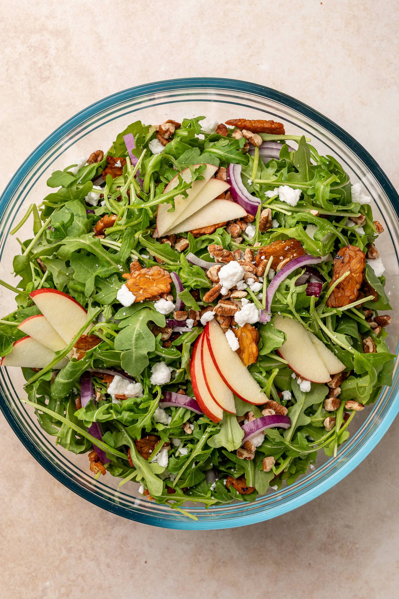 Apple arugula ingredients being mixed in a large bowl, before dressing.
