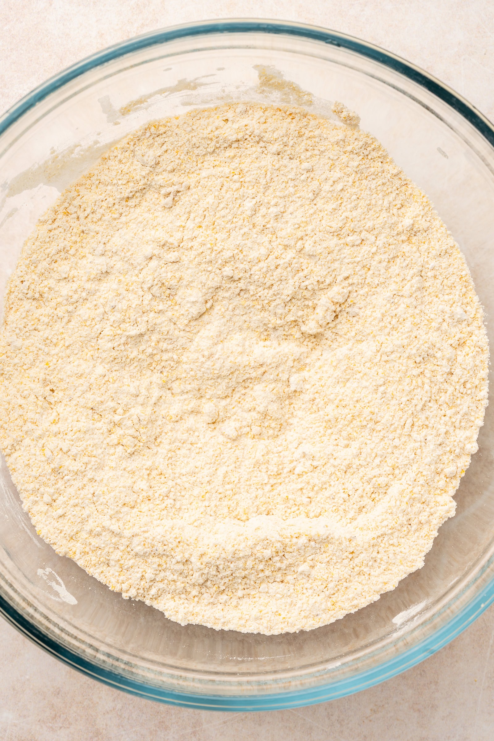 Cornbread, all-purpose flour, salt, and leavening agents mixed in a medium-sized glass bowl.