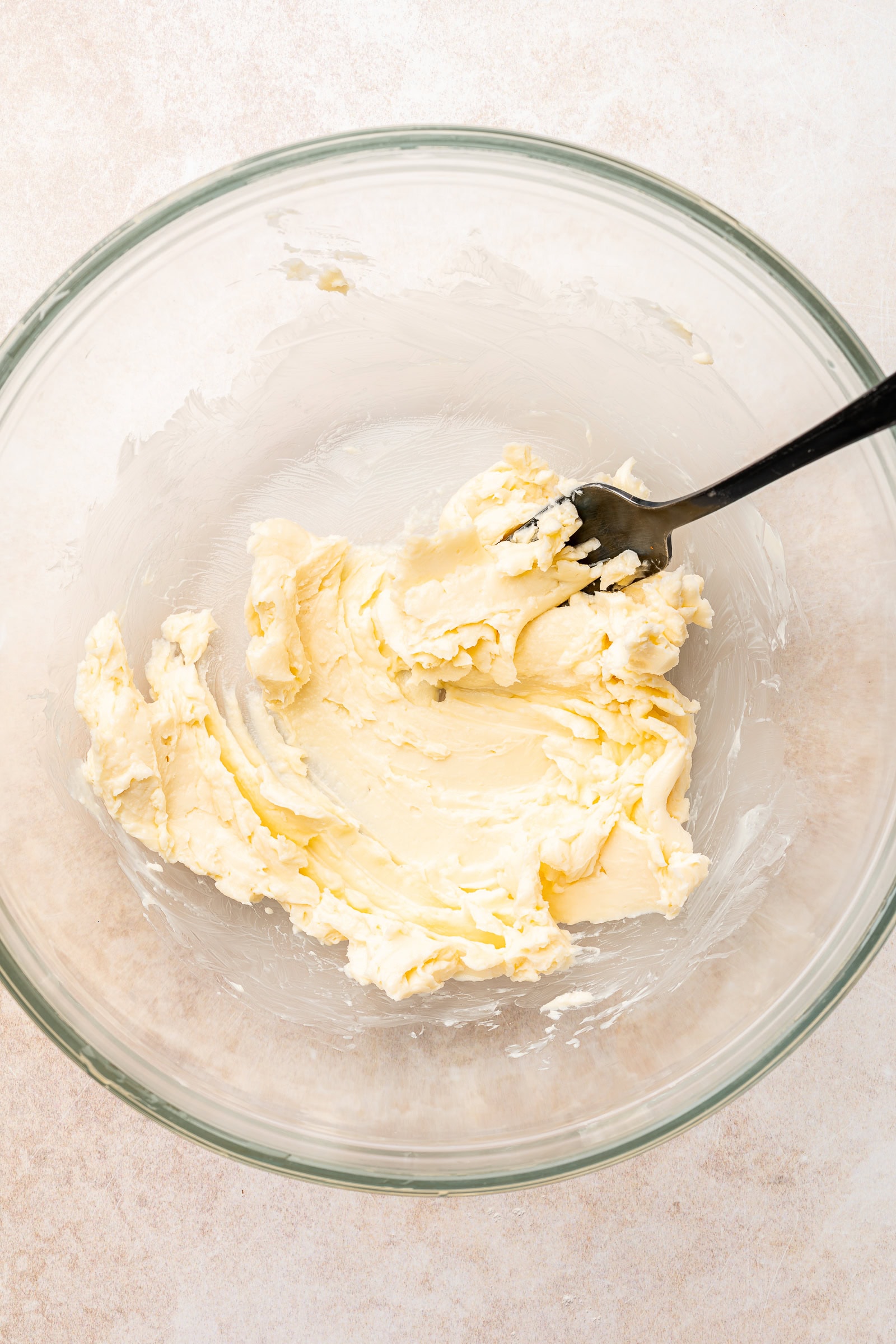 Room temperature butter being whipped with a fork.