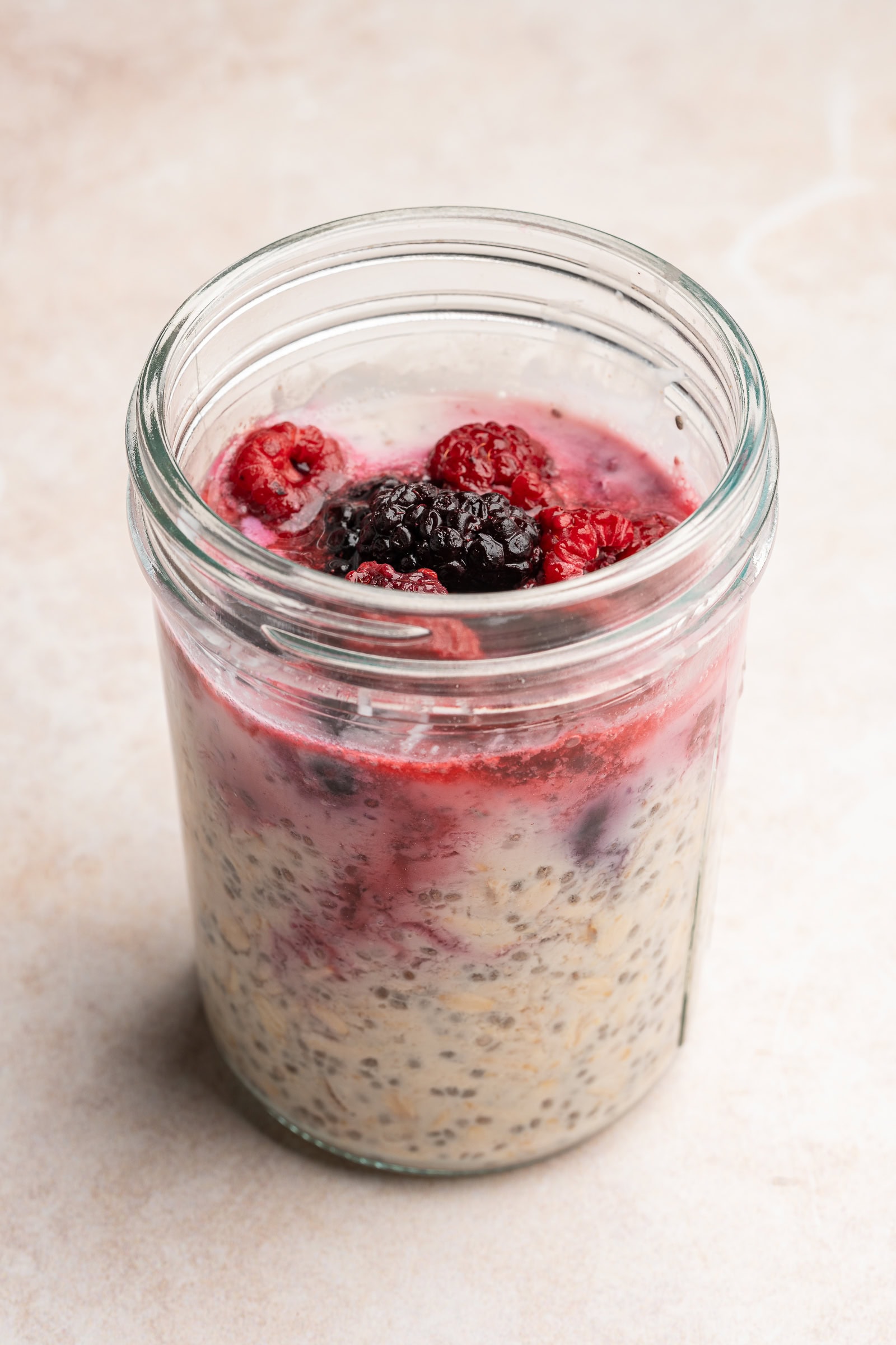 Frozen berries thawed on top of thickened overnight oats.