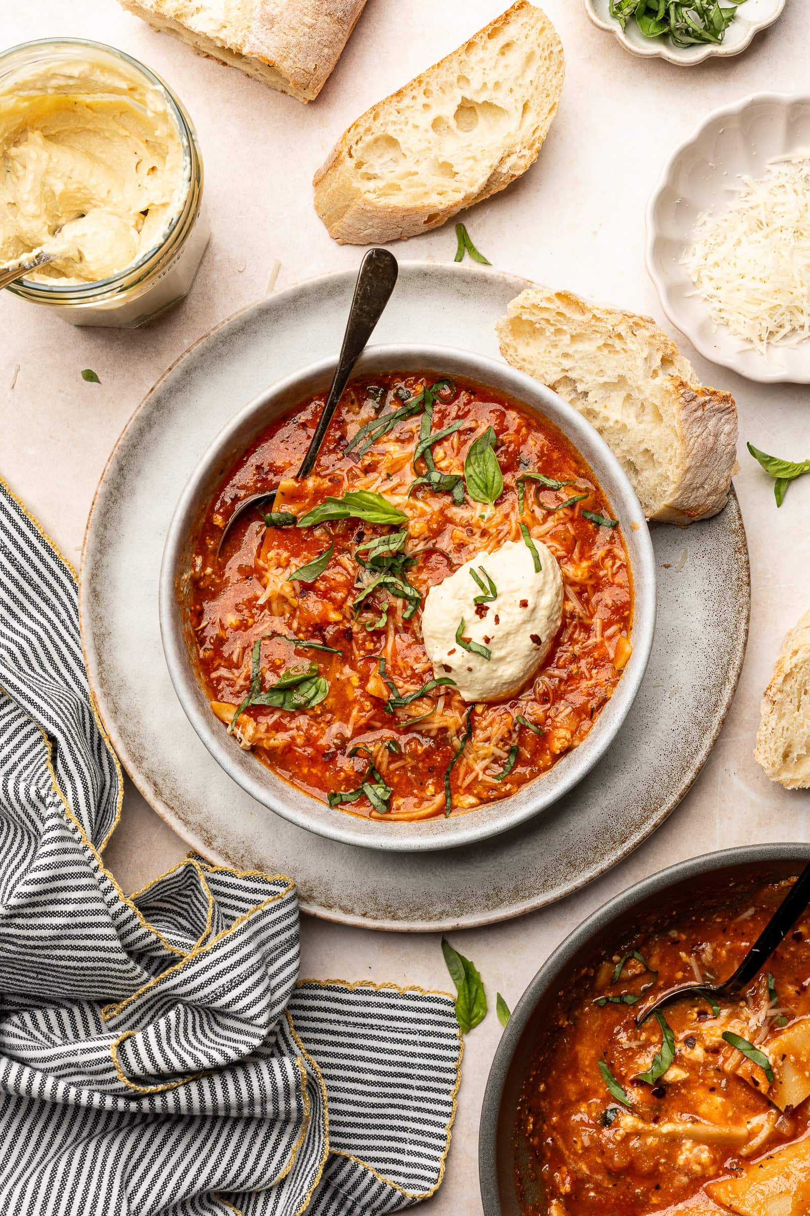 Lasagna soup in a serving bowl with vegan ricotta and garnished with basil.