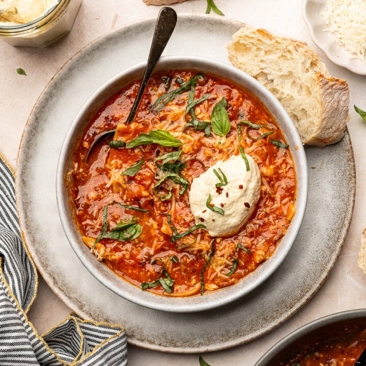 Lasagna soup in a serving bowl with vegan ricotta and garnished with basil.