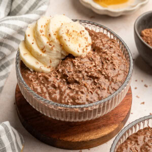 Chocolate banana pudding in a glass serving bowl topped with chocolate shavings and banana slices.
