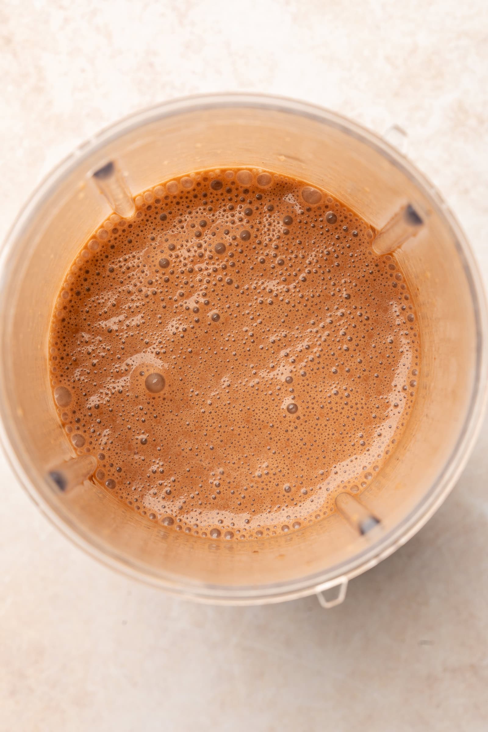 Blended chocolate banana milk mixture in blender cup.