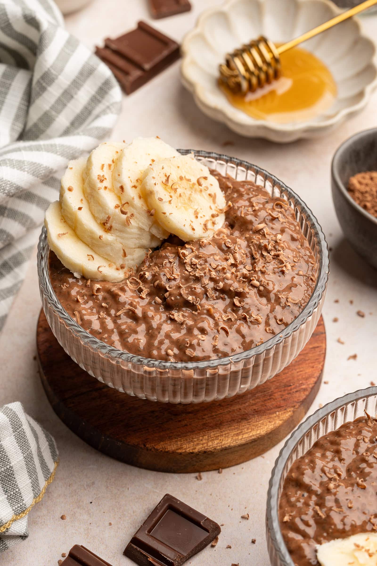 Chocolate banana pudding in a glass serving bowl topped with chocolate shavings and banana slices.