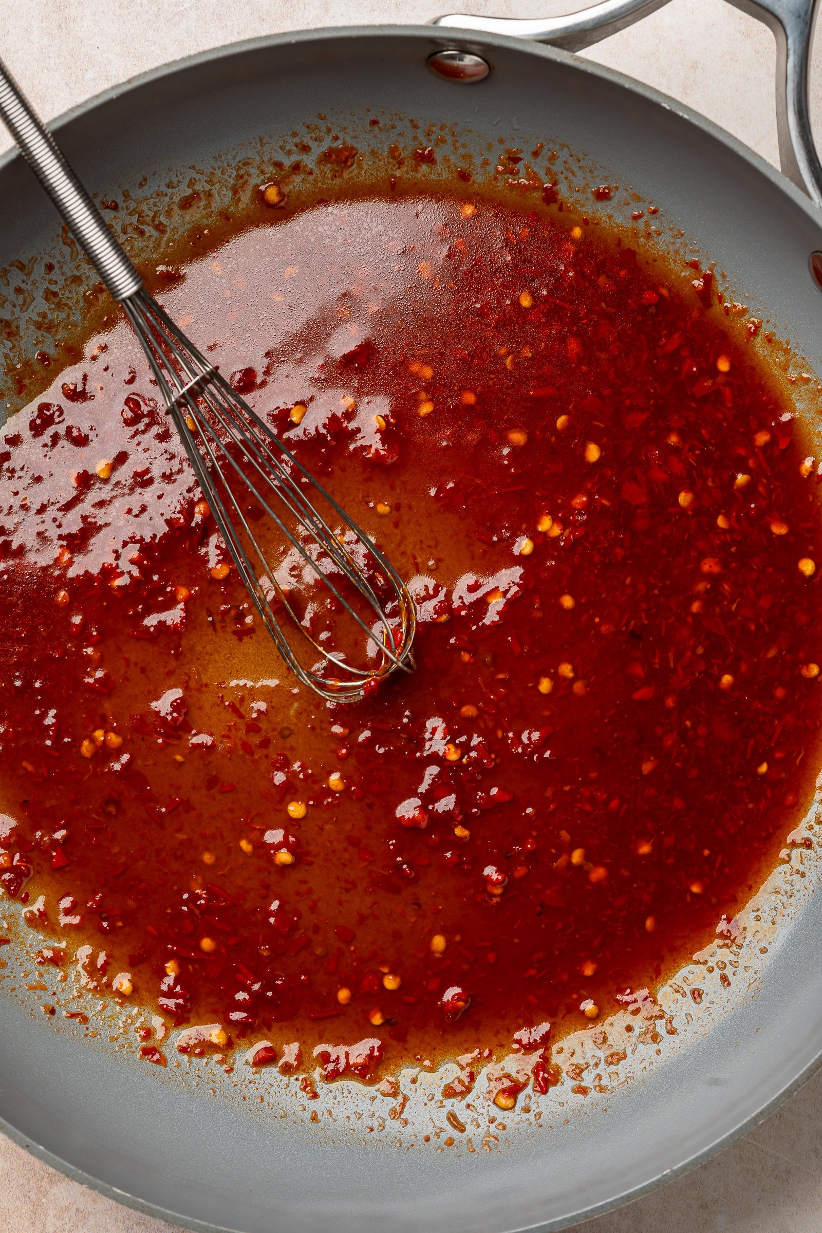 Harissa glaze in frying pan with whisk.
