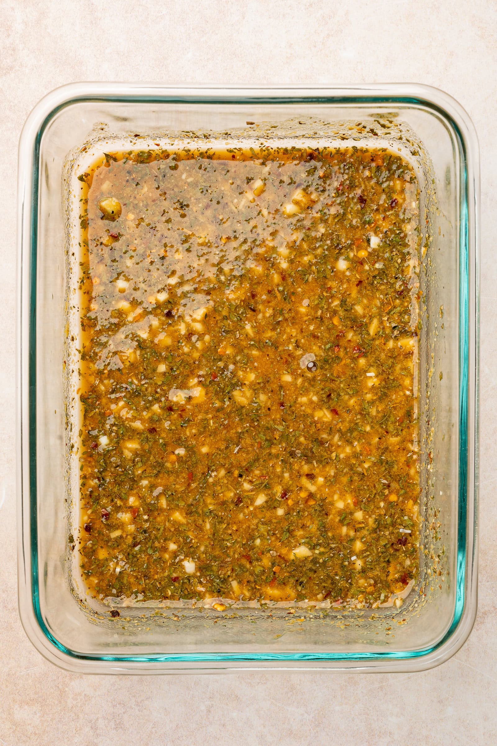 Lemon dried herb marinade mixed together in a rectangle glass Tupperware.