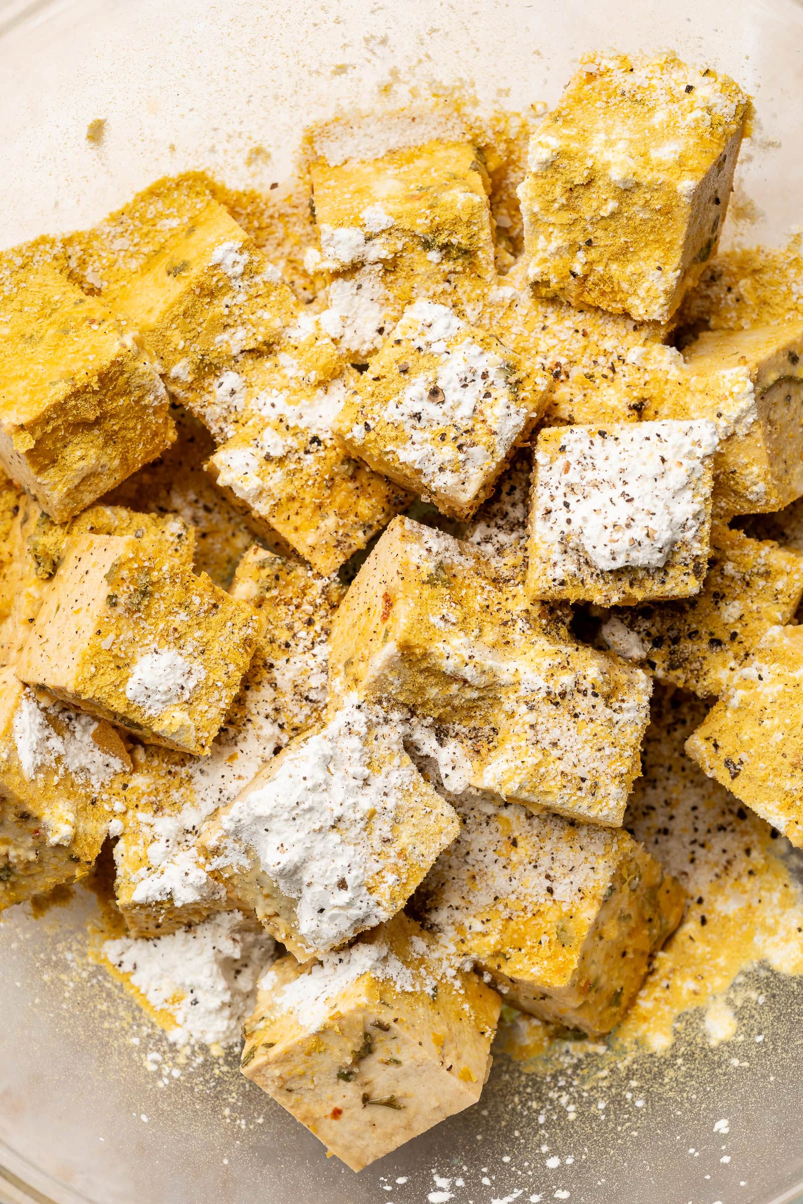 Dry ingredients being mixed into marinated lemon herb tofu.