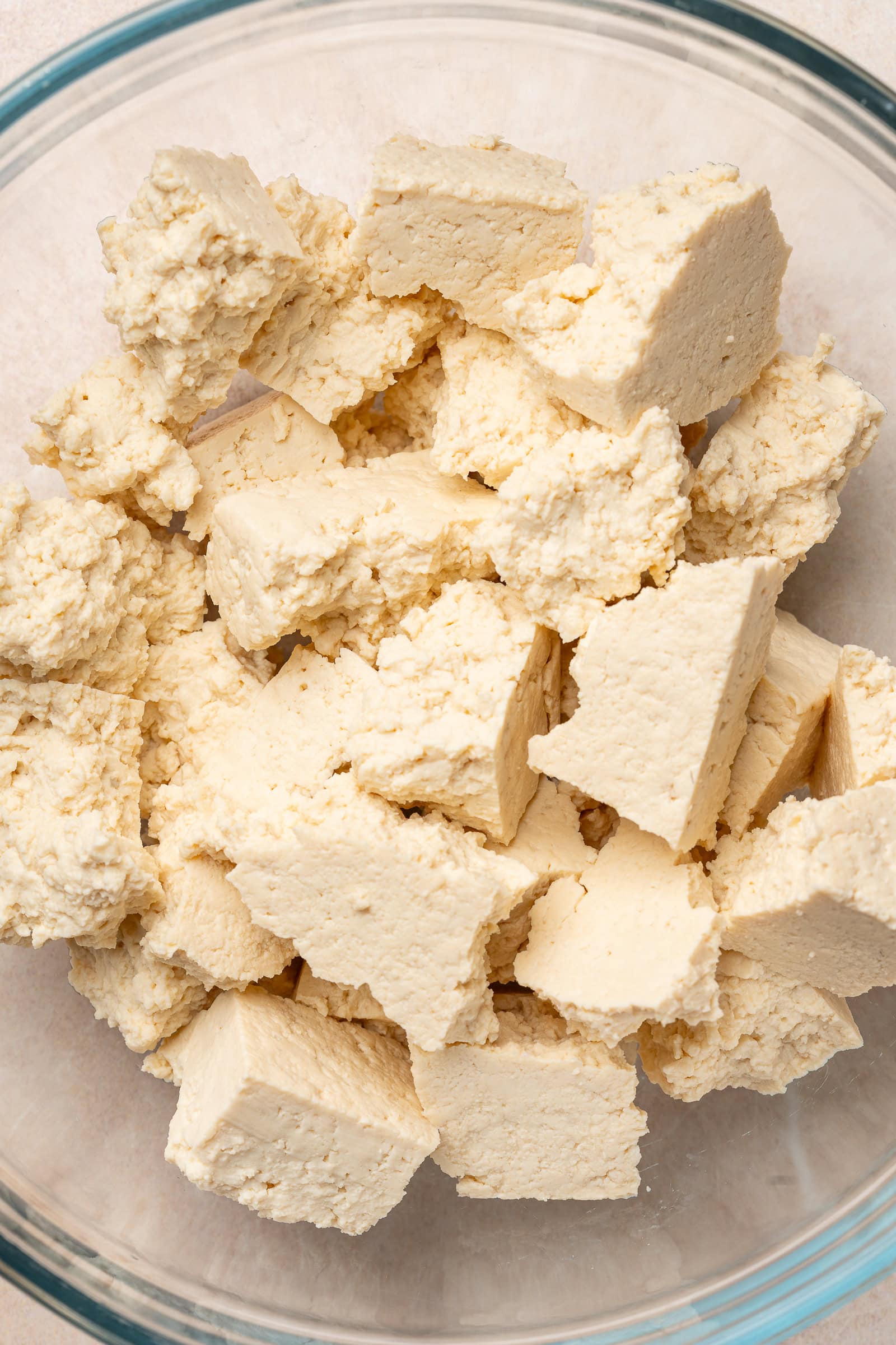 Ripped tofu chunks in a glass bowl.