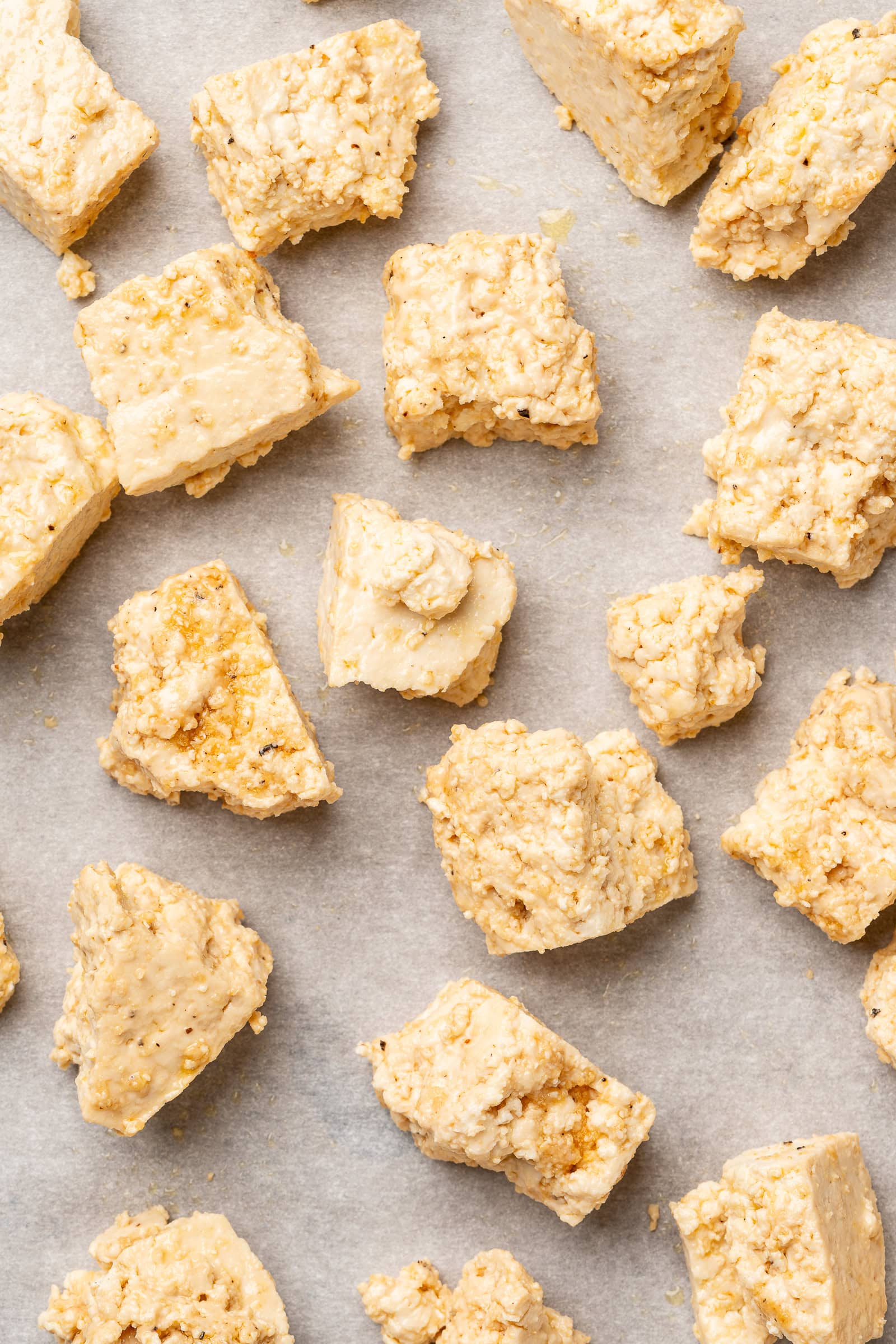 Coated tofu on a parchment lined baking sheet.