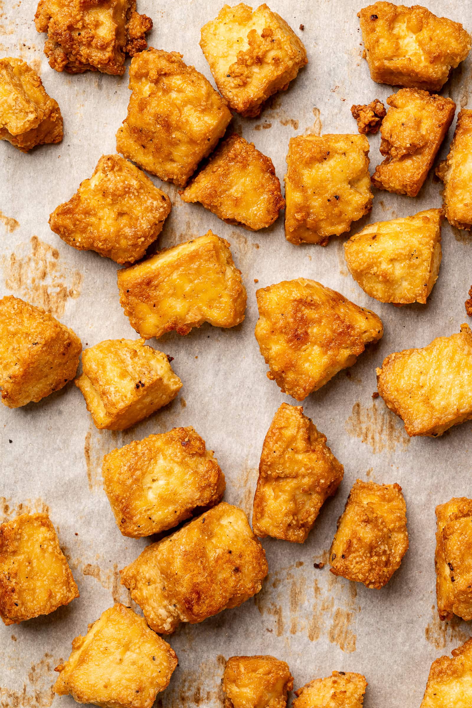 Crispy baked tofu on parchment lined baking sheet.