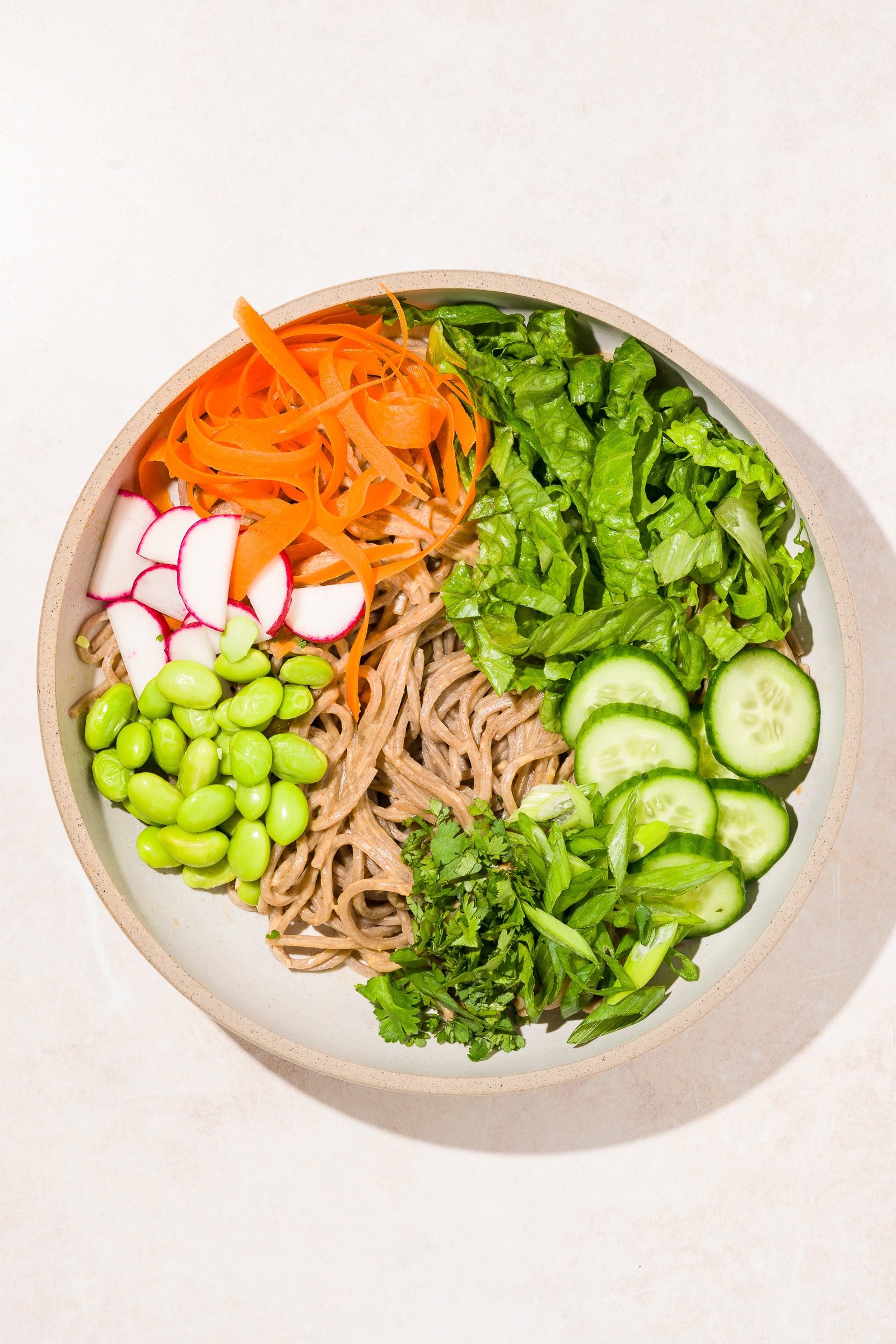 Soba noodles in a shallow bowl with veggies.