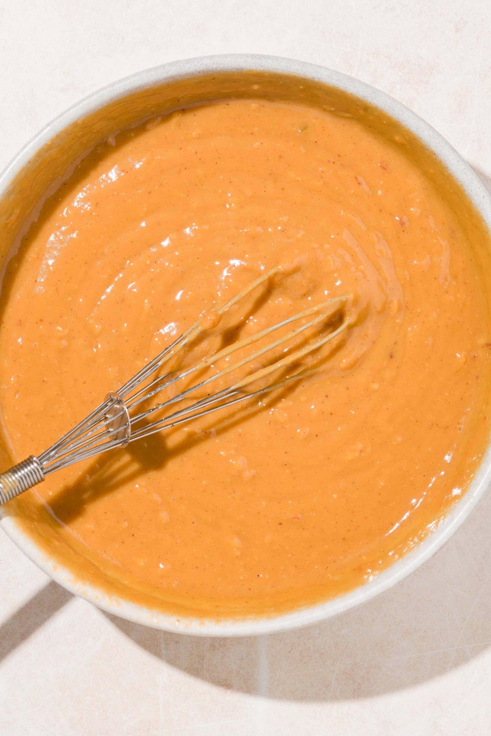 Peanut sauce being whisked in a bowl.