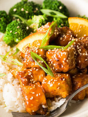 Close-up of crispy orange tofu tossed in orange sauce.