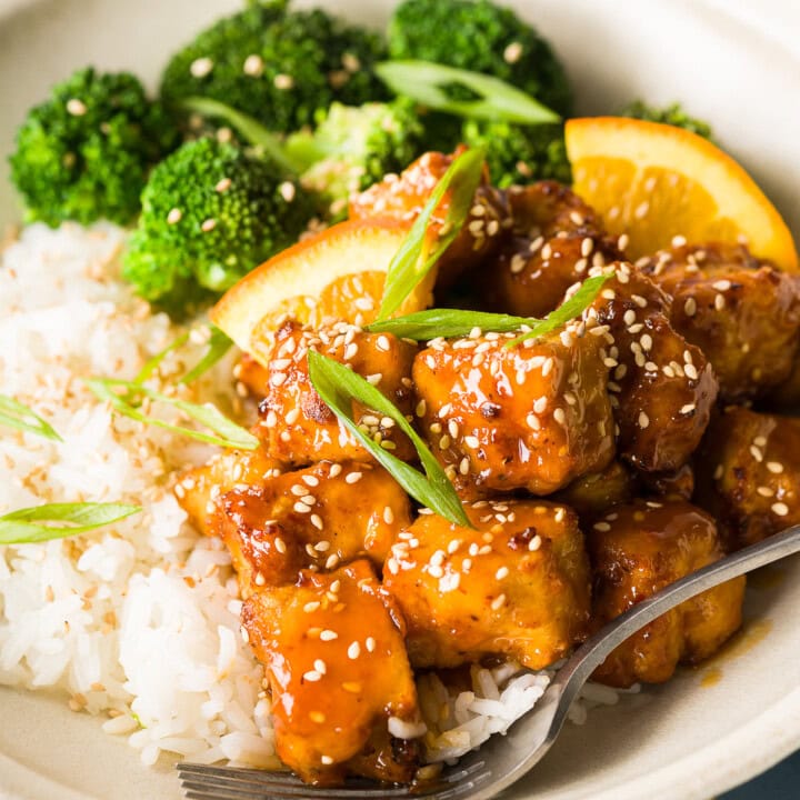 Close-up of crispy orange tofu tossed in orange sauce.