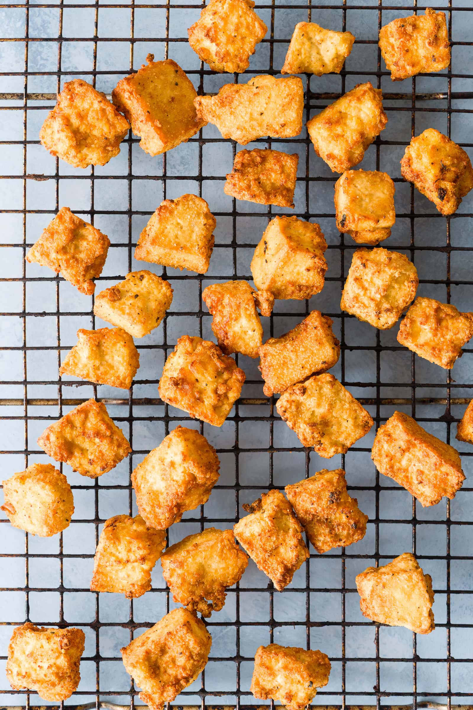 Crispy ripped orange tofu on a cooling rack after air frying.